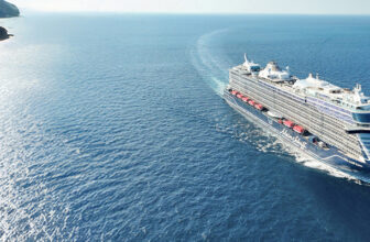 Cruiseschip op zee langs een groene kust