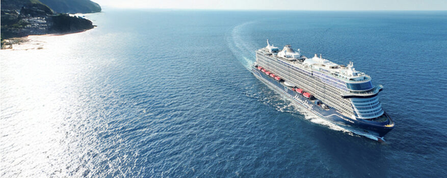 Cruiseschip op zee langs een groene kust